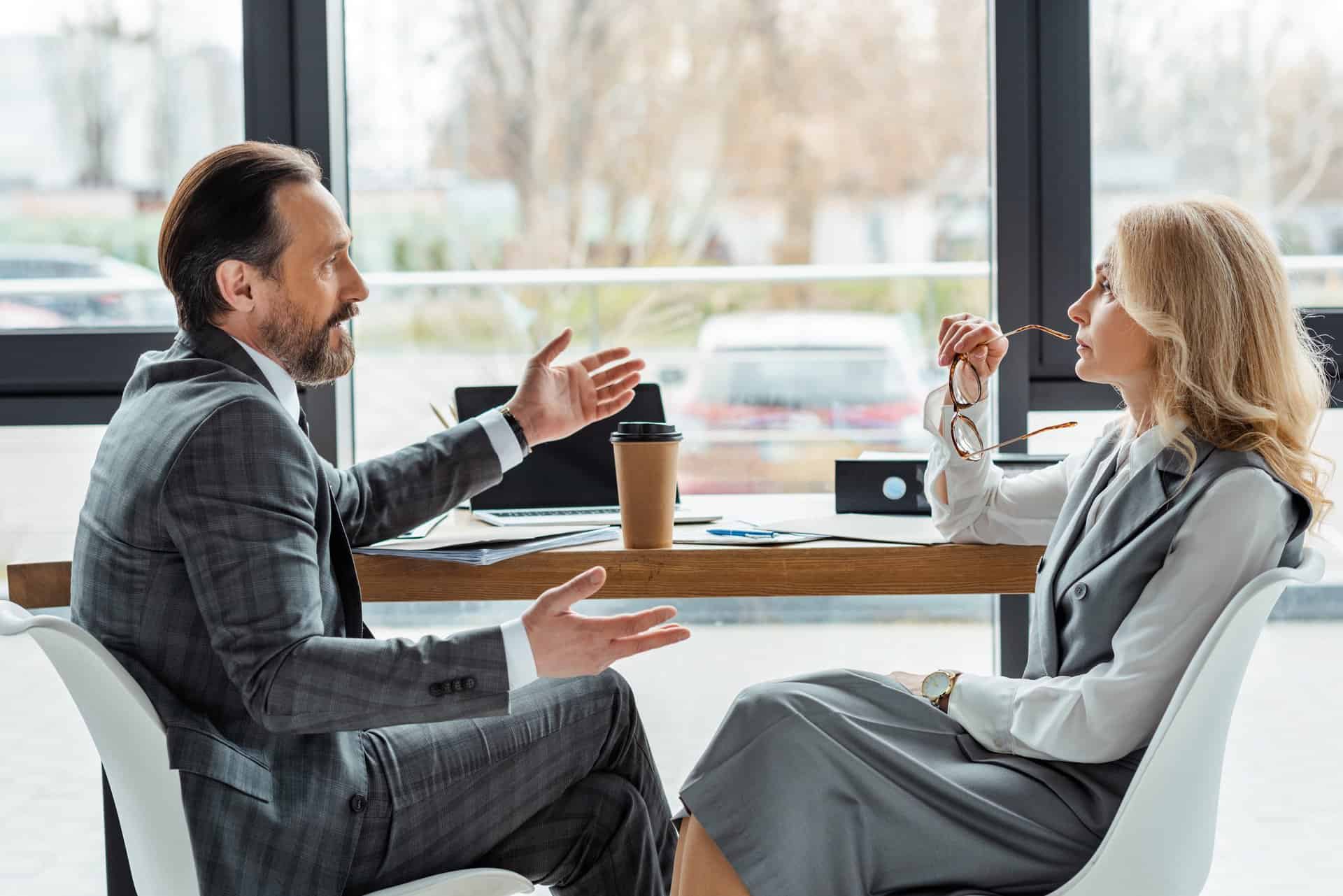 Man & Woman Discussing Business at a Table with Coffee